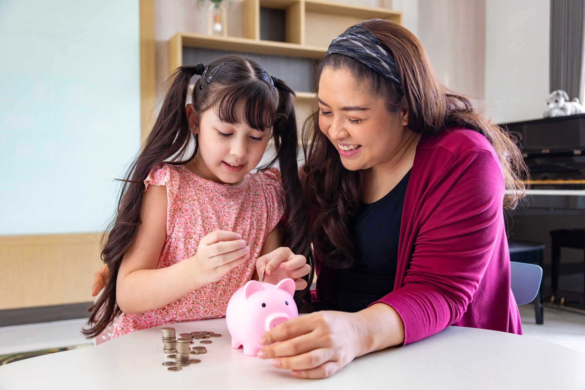 Asian mother is teaching her daughter the saving lesson for investment in education and future planning with copy space